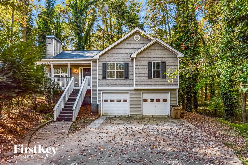 A house with a garage is surrounded by trees.