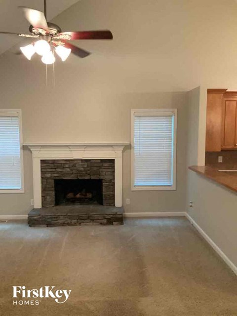 A living room with a fireplace and a ceiling fan.