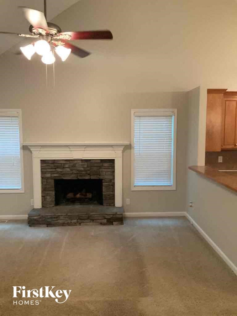 A living room with a fireplace and a ceiling fan.