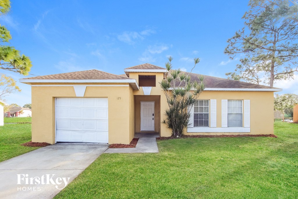 a yellow house with a white garage door and a green lawn