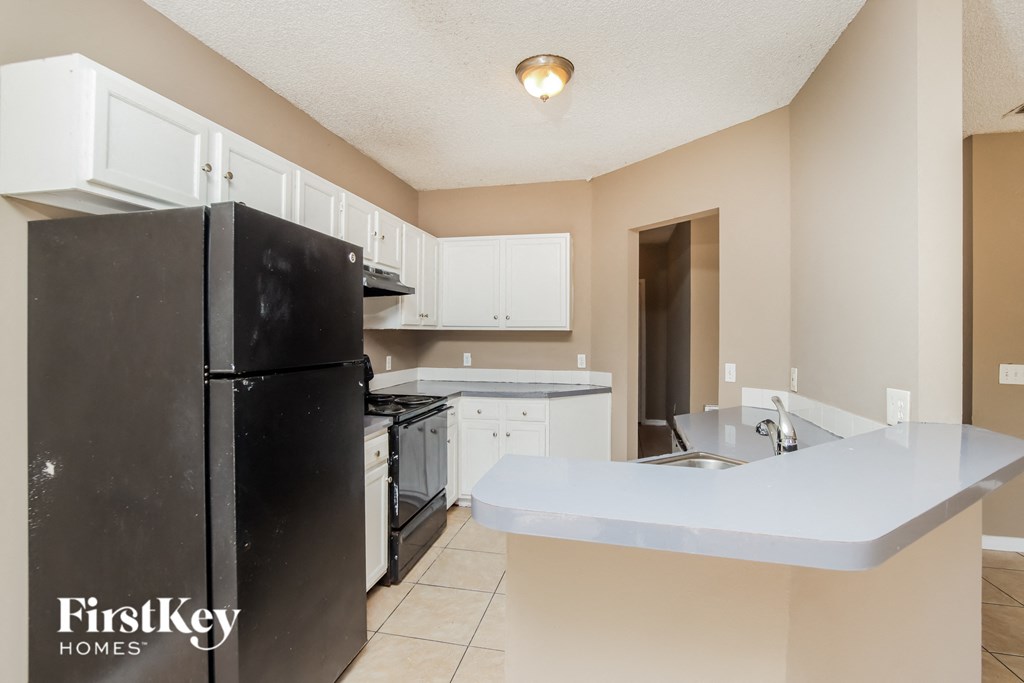 a kitchen with white cabinets and a black refrigerator