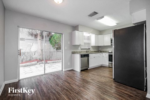 A kitchen with a black refrigerator and wooden floors.