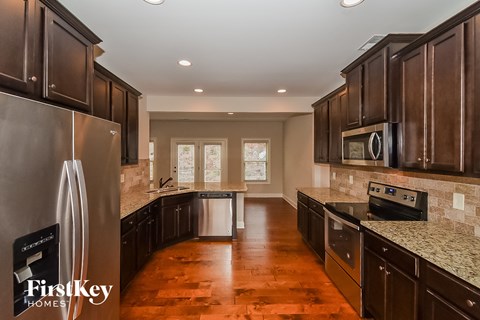 a kitchen with dark wood cabinets and granite counter tops and stainless steel appliances