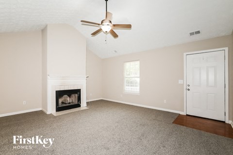A spacious room with a fireplace and a ceiling fan.