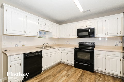 A kitchen with white cabinets and black appliances.