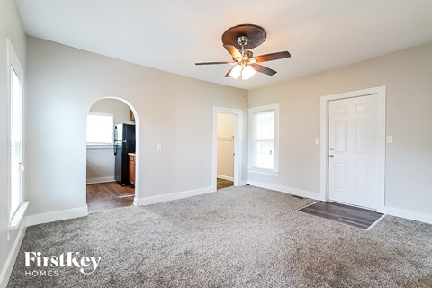 a living room with carpet and a ceiling fan