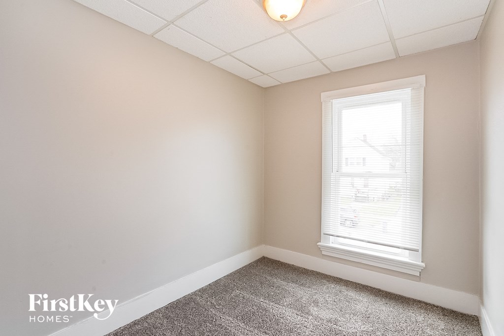 a bedroom with a window and a carpeted floor