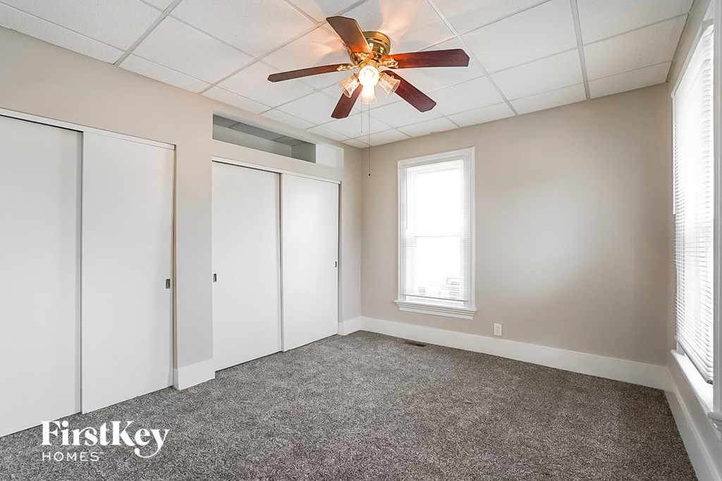 an empty room with a ceiling fan and three closets