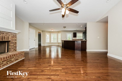 an empty living room with a fireplace and a ceiling fan