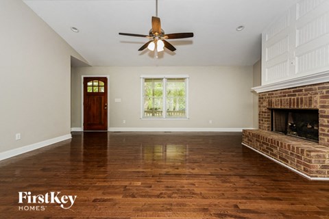 a living room with a brick fireplace and a ceiling fan