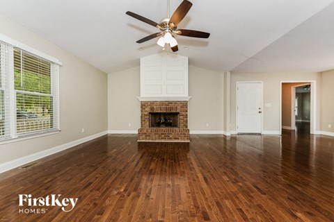 an empty living room with a fireplace and a ceiling fan