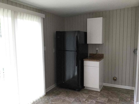 A black refrigerator in a kitchen with a white countertop and cabinet.