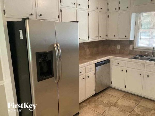 a kitchen with white cabinets and a stainless steel refrigerator