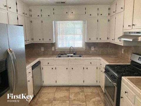 a kitchen with white cabinets and a sink and a refrigerator