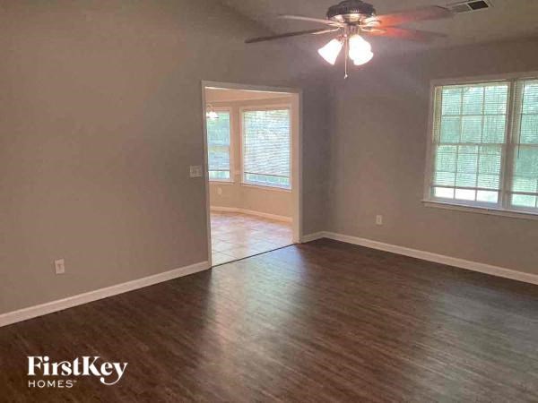an empty living room with a wood floor and a ceiling fan