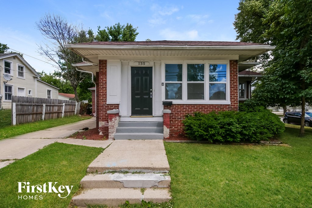 A house with a brick facade and a black door is for sale.
