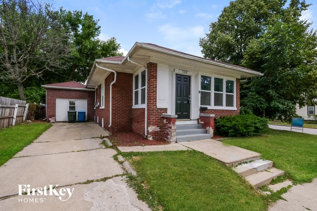 A brick house with a white door and windows is for sale.