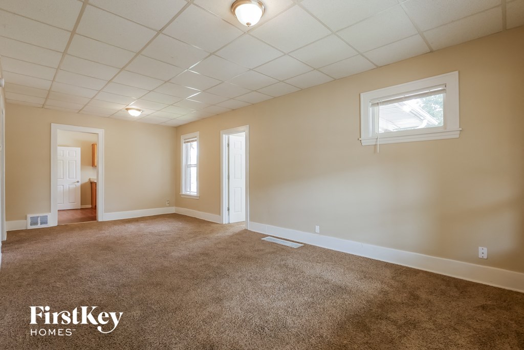 A spacious room with a carpeted floor and a window.
