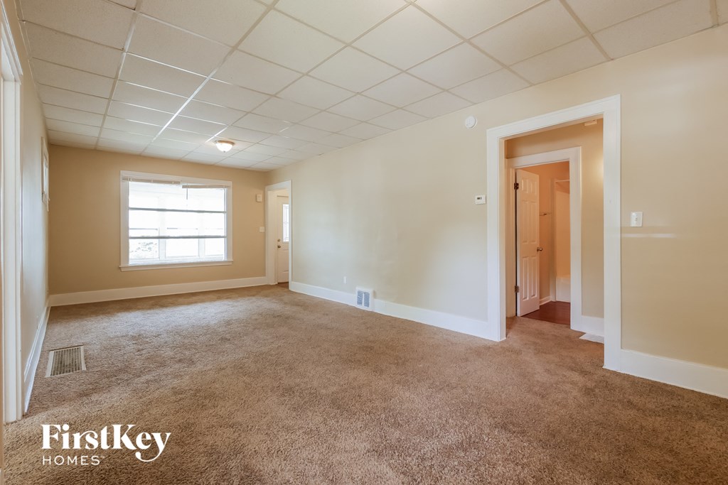 A spacious room with a carpeted floor and a door on the right side.