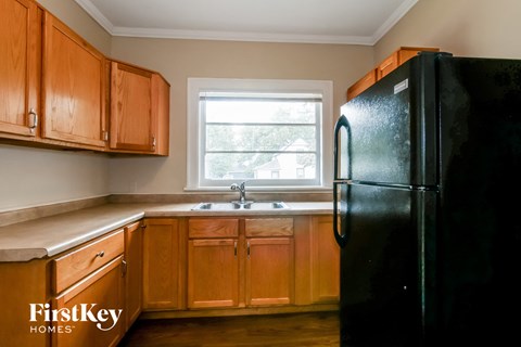 A kitchen with wooden cabinets and a black refrigerator.