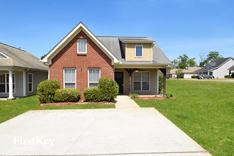 A brick house with a white window and a grey roof.
