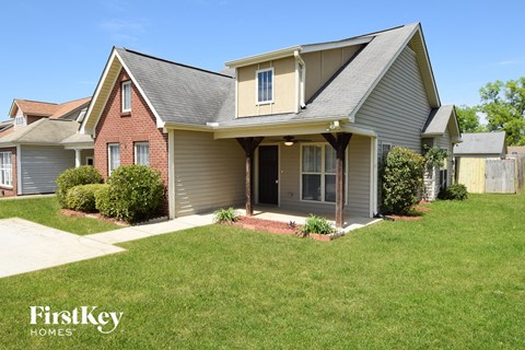A house with a grey roof and a red brick wall is for sale.