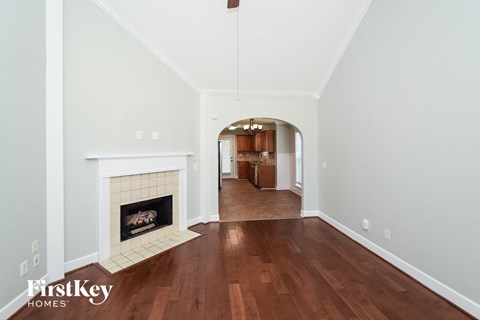 A spacious room with a fireplace and wooden floors.