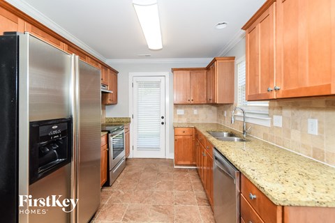 A kitchen with a stainless steel refrigerator and wooden cabinets.