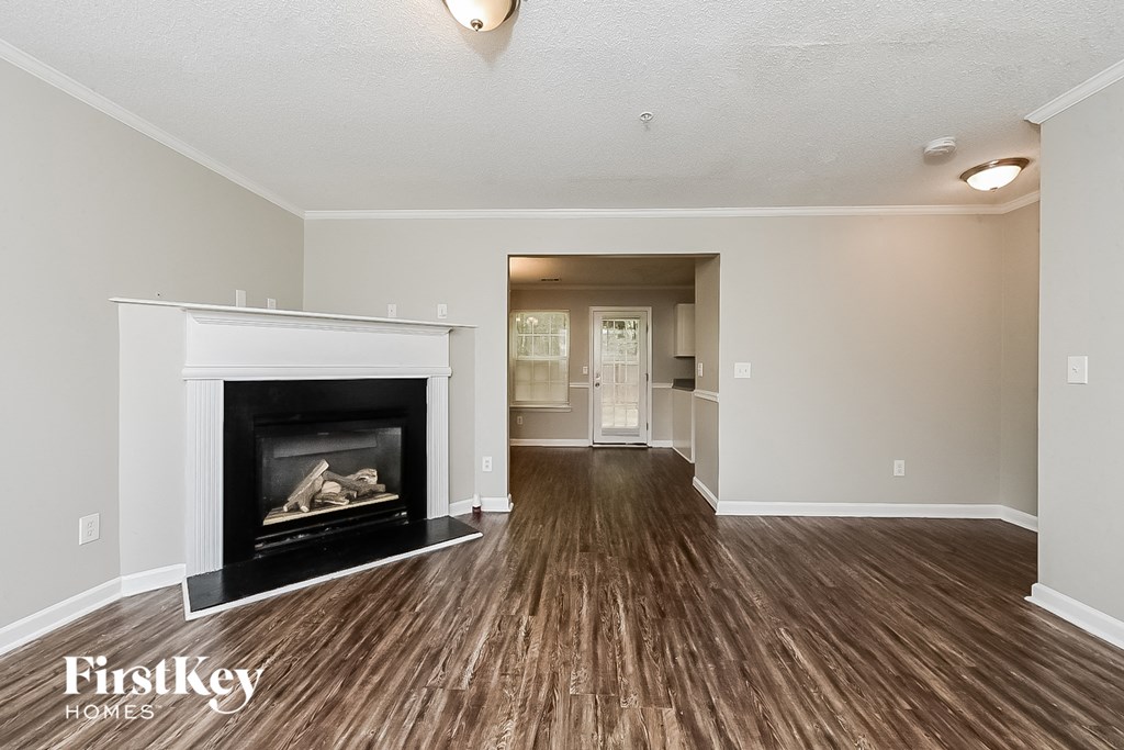 A spacious room with a fireplace and wooden floors.