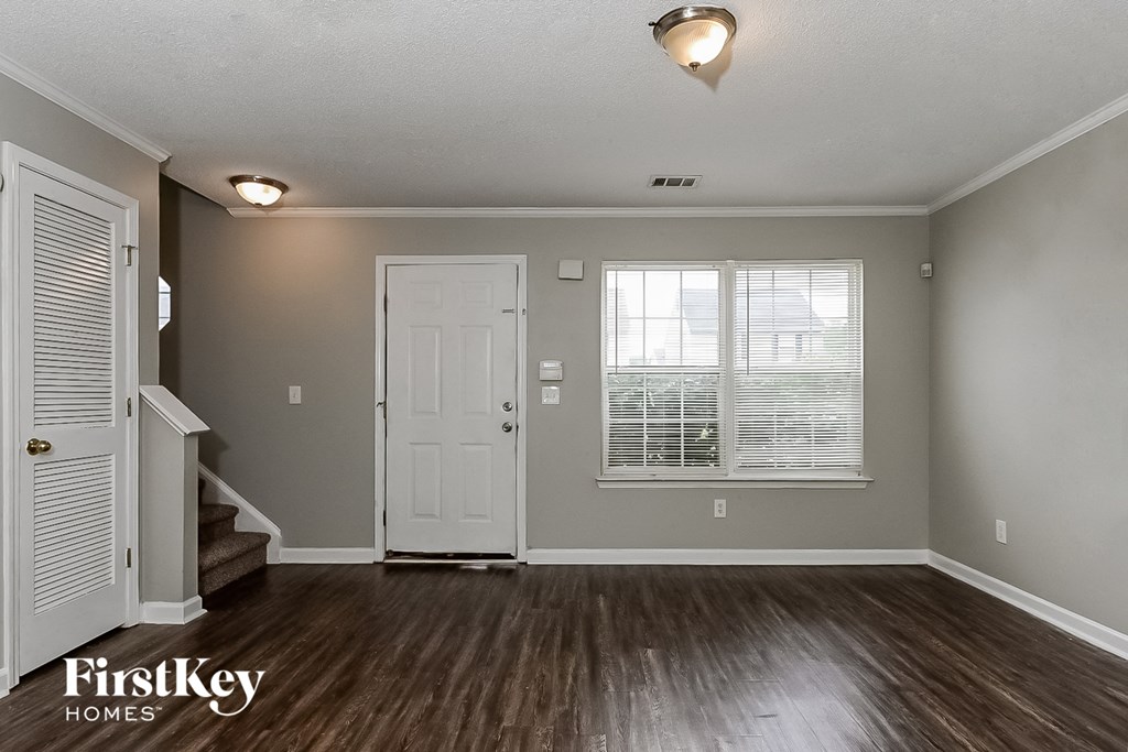 A room with wooden floors and a window with blinds.