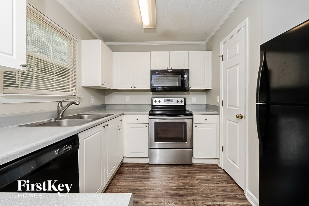 A kitchen with white cabinets and a black fridge.