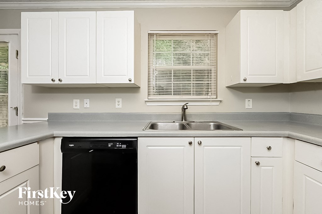 A kitchen with white cabinets and a black dishwasher.