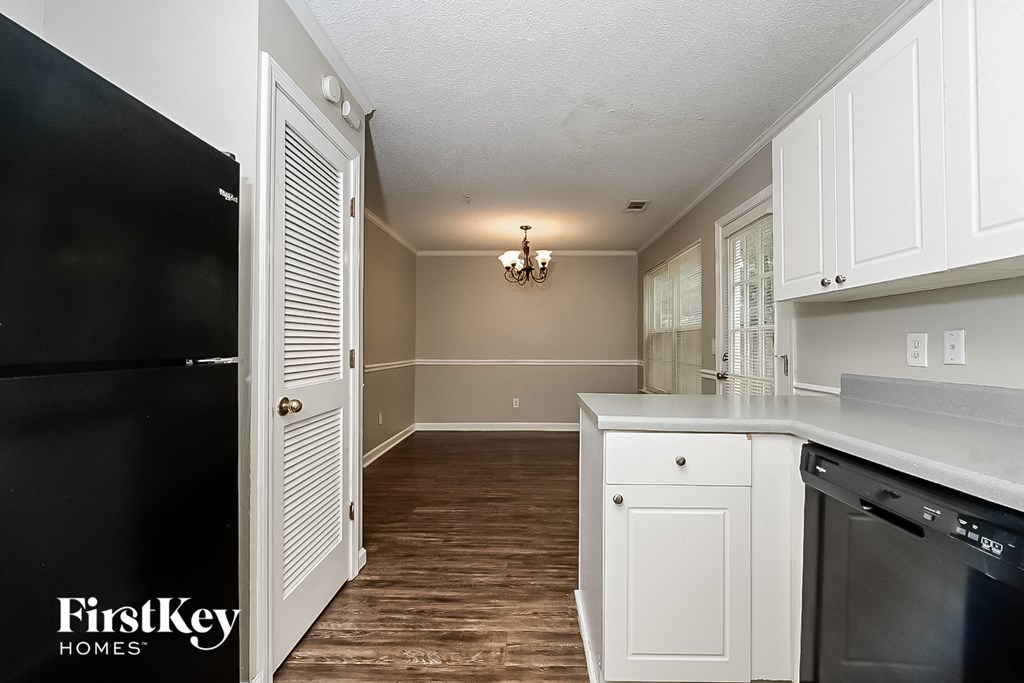 A kitchen with a black fridge and white cabinets.