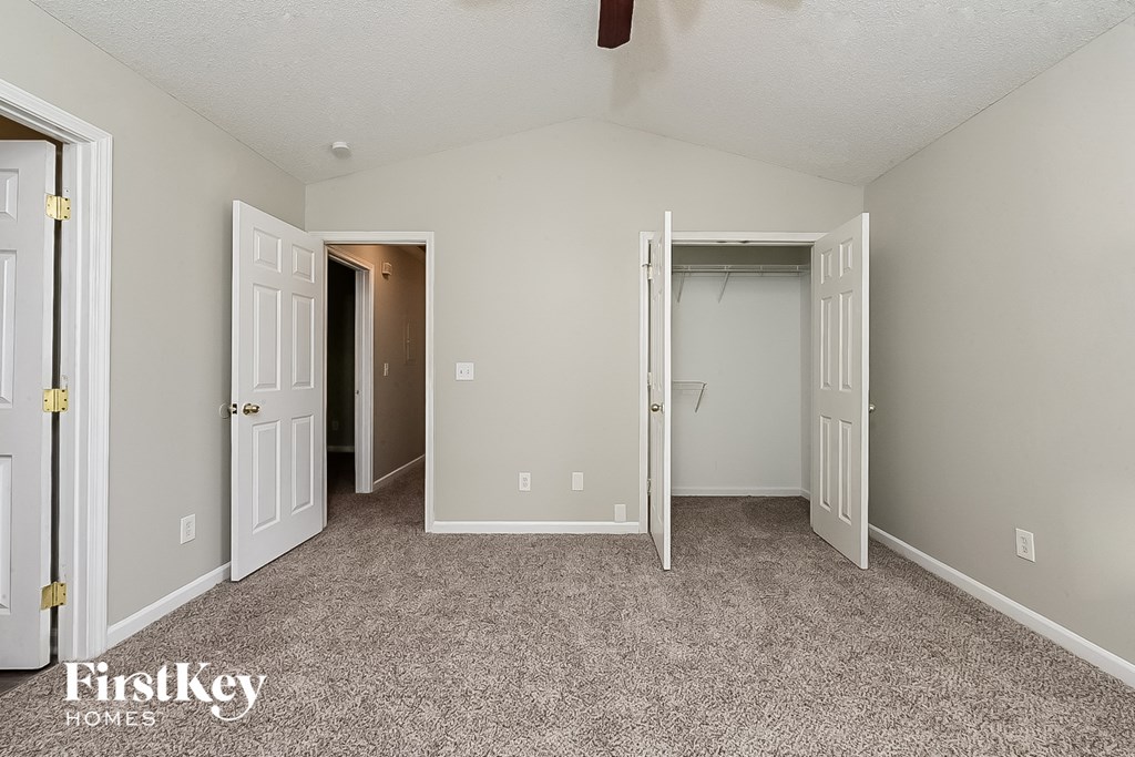 A room with a carpeted floor and a ceiling fan.