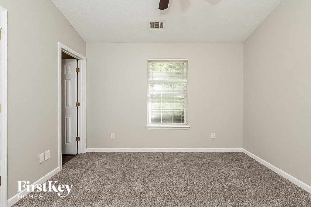 A room with a carpeted floor and a window with blinds.
