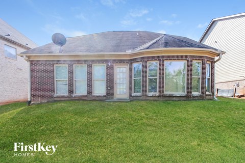 the front of a brick house with a yard and grass
