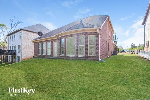 the backyard of a brick house with a grass lawn and a gazebo