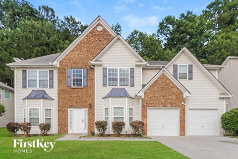 a brick house with white siding and white garage doors