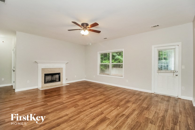 an empty living room with a ceiling fan and a fireplace