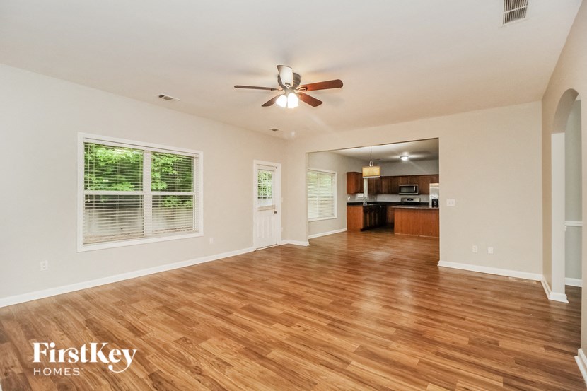 an empty living room with wood flooring and a ceiling fan