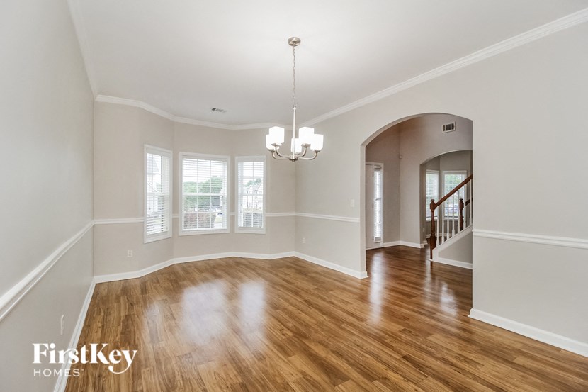 an empty living room with a hardwood floor and a chandelier