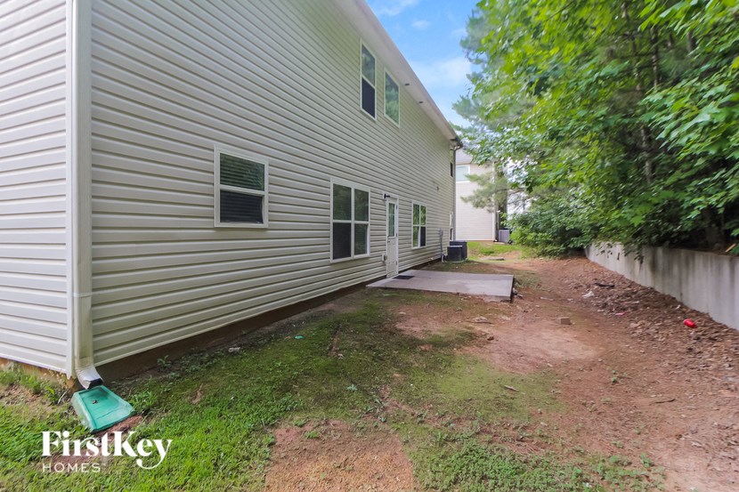 the side of a white house with a dirt path next to it