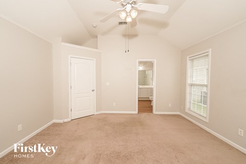 A spacious room with a ceiling fan and carpeted floor.