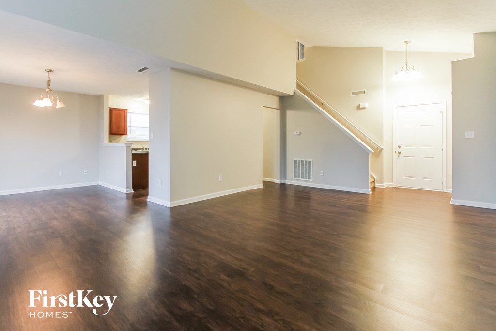 an empty living room with wood floors and a staircase