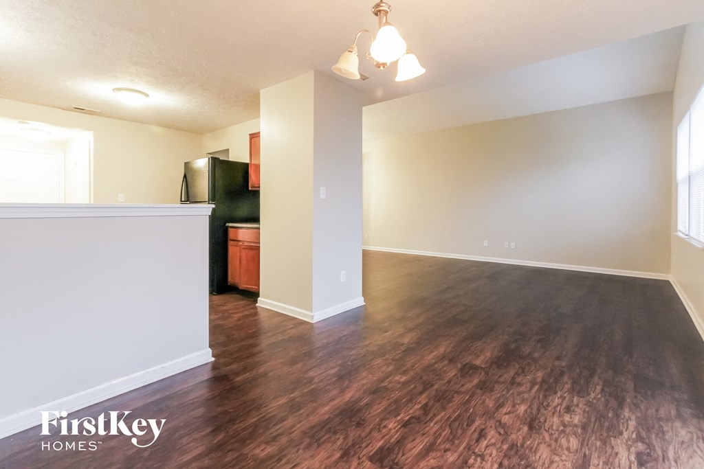 the living room and dining room of an empty house with wood flooring