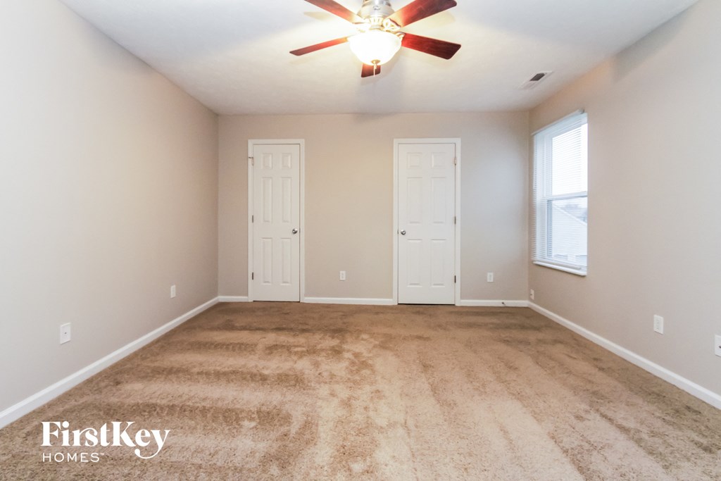 the spacious living room with carpeted floors and a ceiling fan
