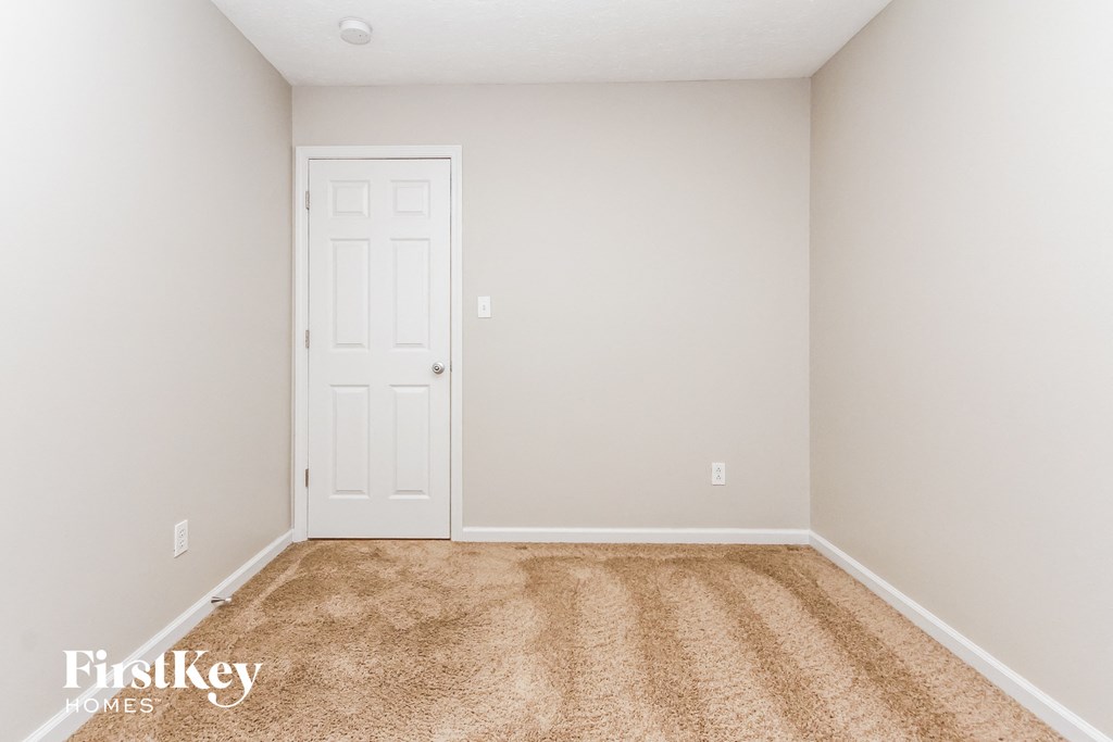 a bedroom with a white door and a carpeted floor