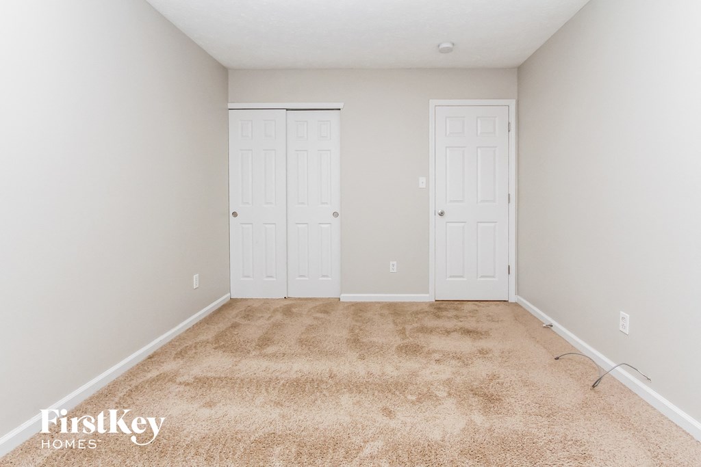 a bedroom with two doors and a carpeted floor