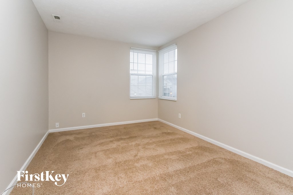 a bedroom with a carpeted floor and two windows