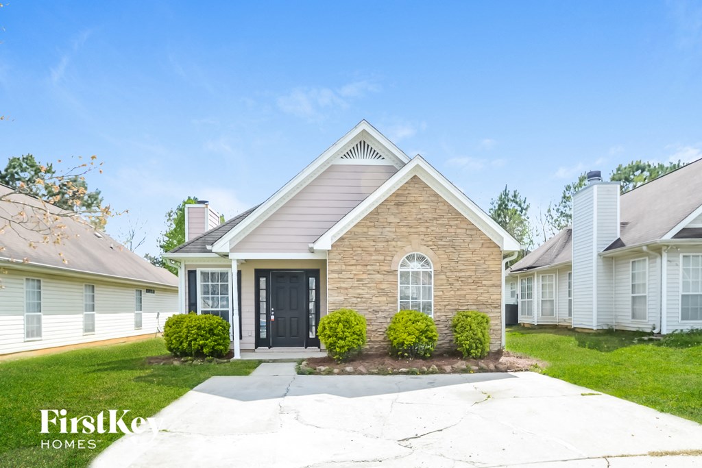 a small brick house with a black door and a lawn